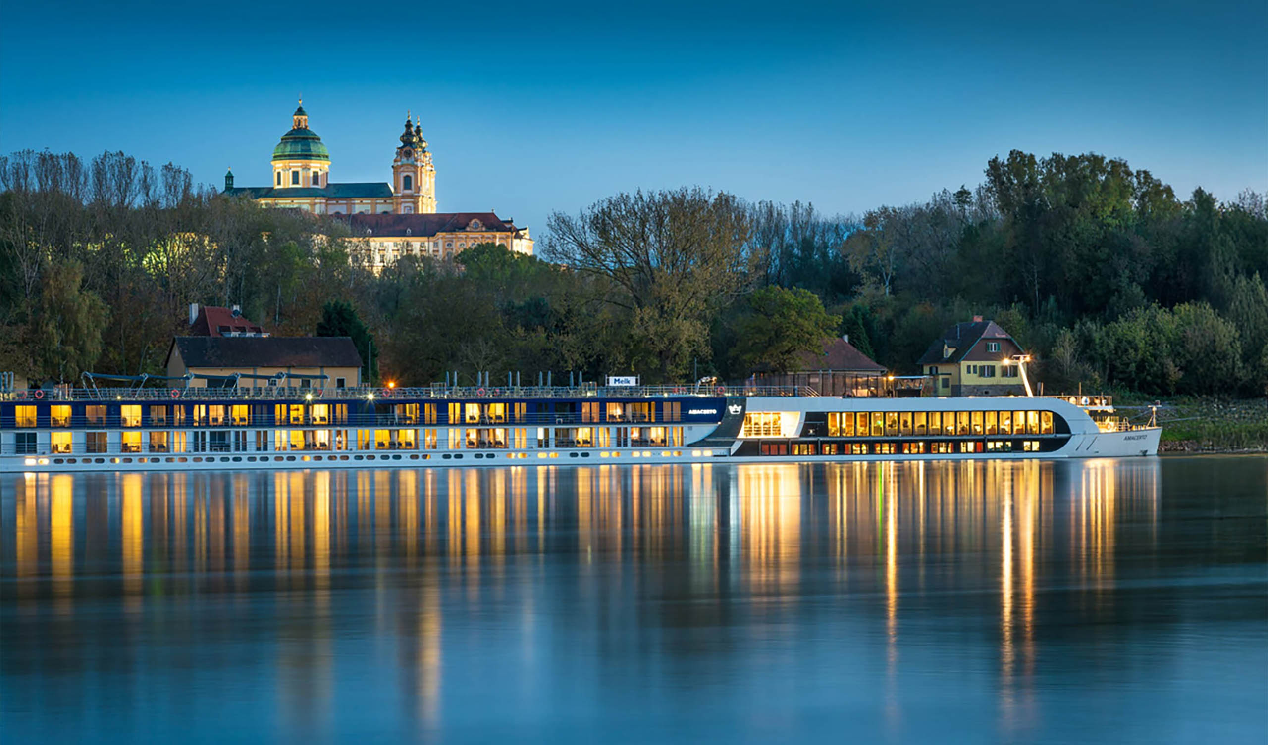 Donauschifffahrt bei Nacht – Wachau erleben Abendliche Donauschifffahrt vor der Wachau mit beleuchtetem Flusskreuzfahrtschiff und Stift im Hintergrund